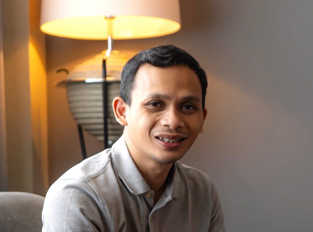Asian Indonesian Man Using Tablet While Relaxing in Cozy Living Room